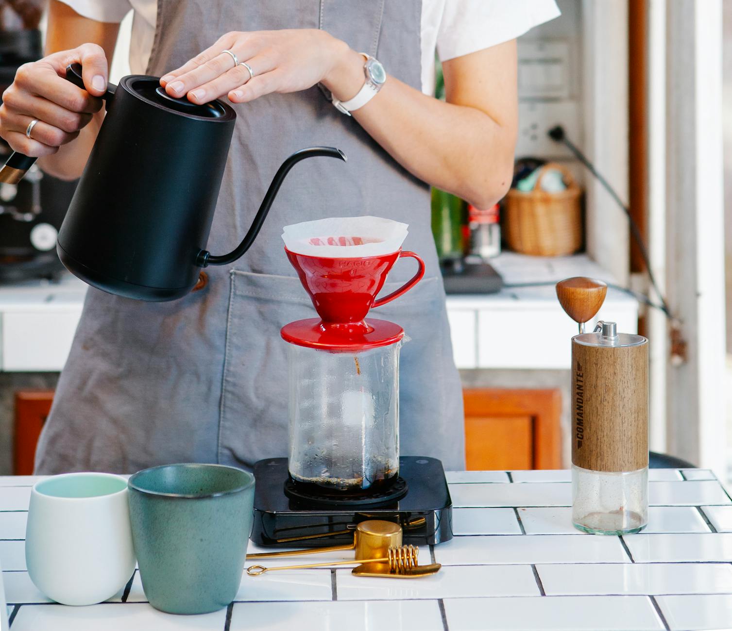 female barista using filter drippers while pouring fresh coffee - pour-over coffee - Fair Coffee Blog - coffee drink recipes