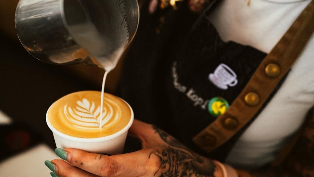 woman pouring milk to coffee at cafe - Café con Leche - recipe - coffee-making at home - fair coffee