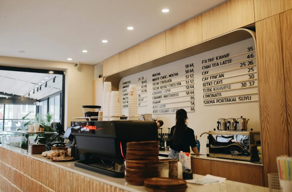 worklife balance coffee shop owner - price - Contemporary café interior with a barista and espresso machine, showcasing a modern menu display.