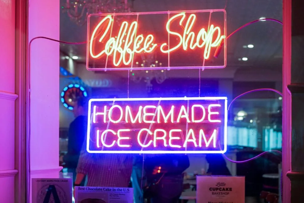 Vibrant neon signs for a coffee shop and homemade ice cream displayed indoors.