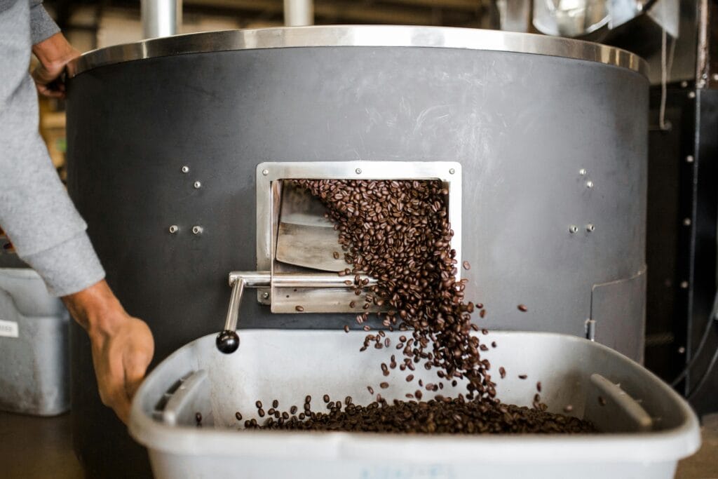 start a coffee business
Close-up of coffee beans being poured from a roasting machine into a container during the coffee roasting process.