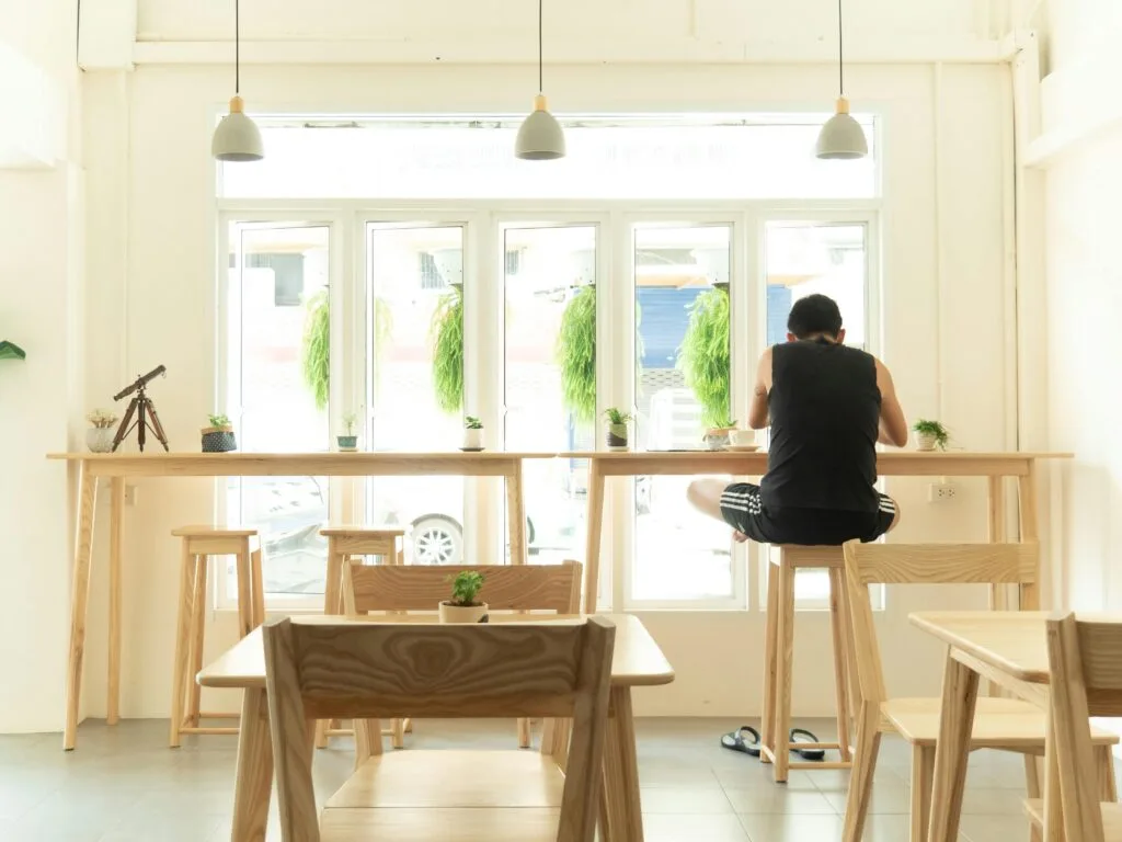 Bright and airy minimalist coffee business shop interior featuring wooden seating, natural light, and a relaxed atmosphere.