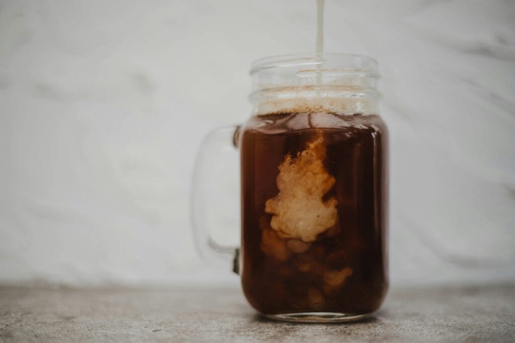 Close-up of cold brew coffee with cream swirling in a mason jar. Perfect for beverage themes.